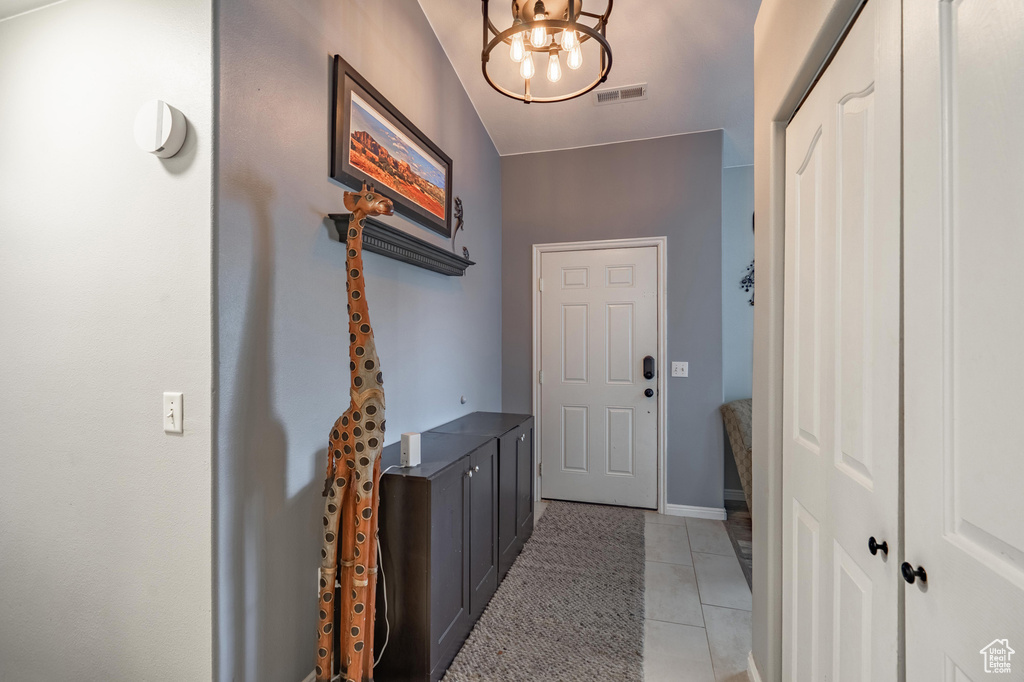 Entryway featuring a chandelier, light tile patterned floors, and baseboards