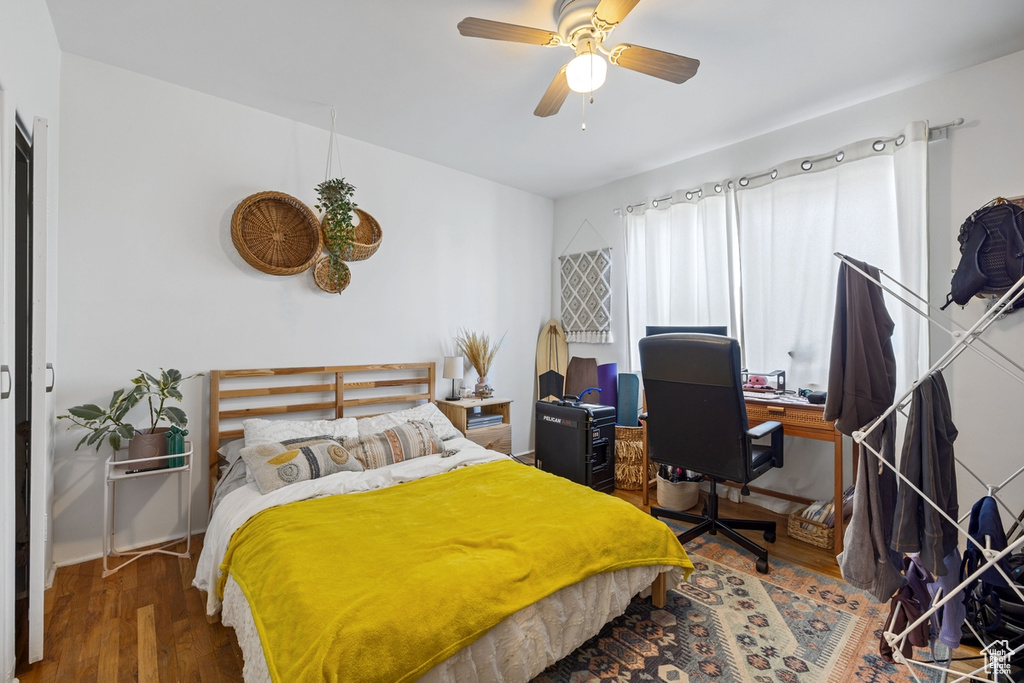 Bedroom with wood finished floors, an office area, and ceiling fan