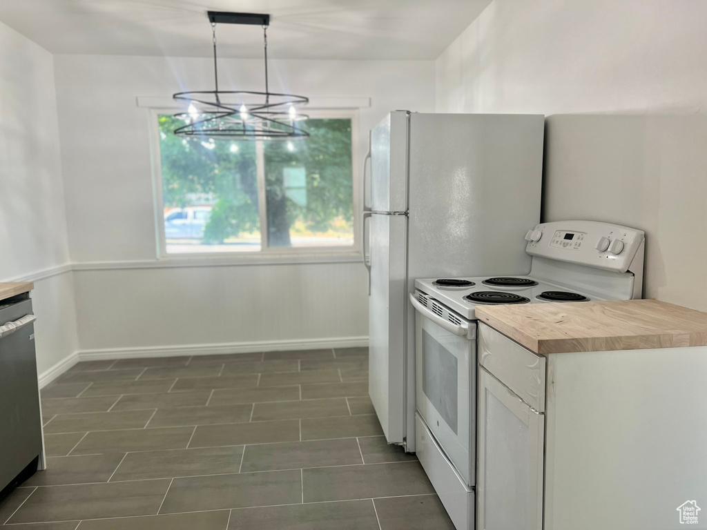 Kitchen with white range with electric cooktop, baseboards, a chandelier, white cabinets, and decorative light fixtures