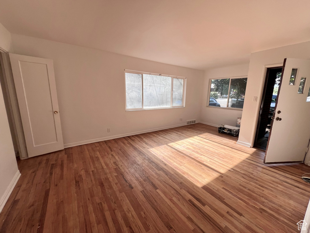 Unfurnished living room featuring wood finished floors and baseboards