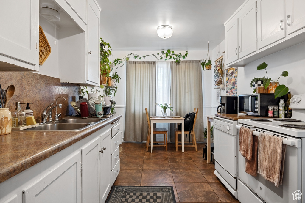 Kitchen featuring white appliances, a sink, decorative backsplash, and white cabinets
