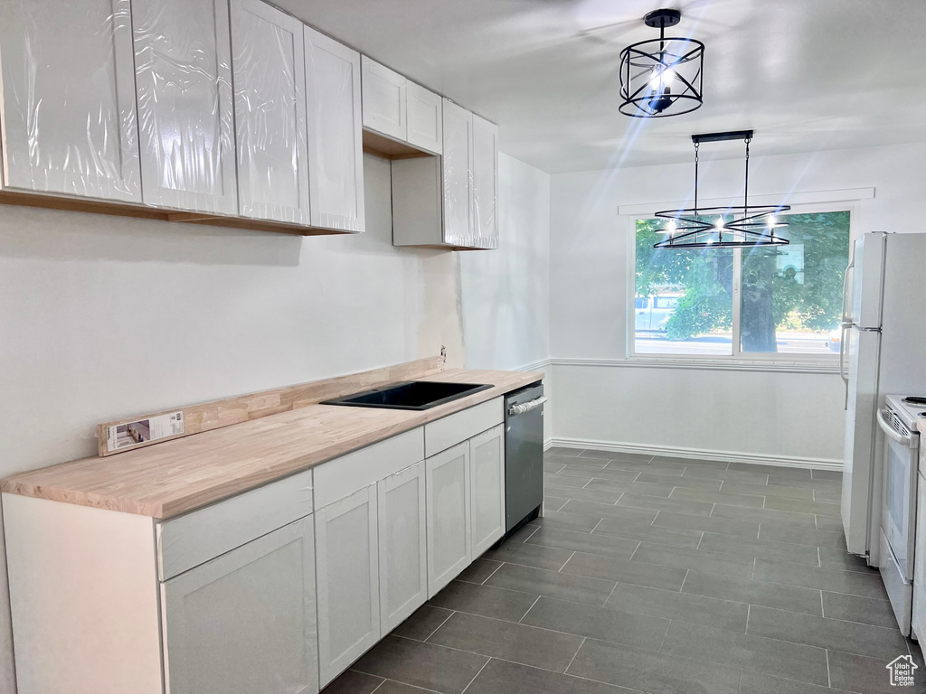 Kitchen with stainless steel dishwasher, white range with electric stovetop, white cabinets, light countertops, and baseboards