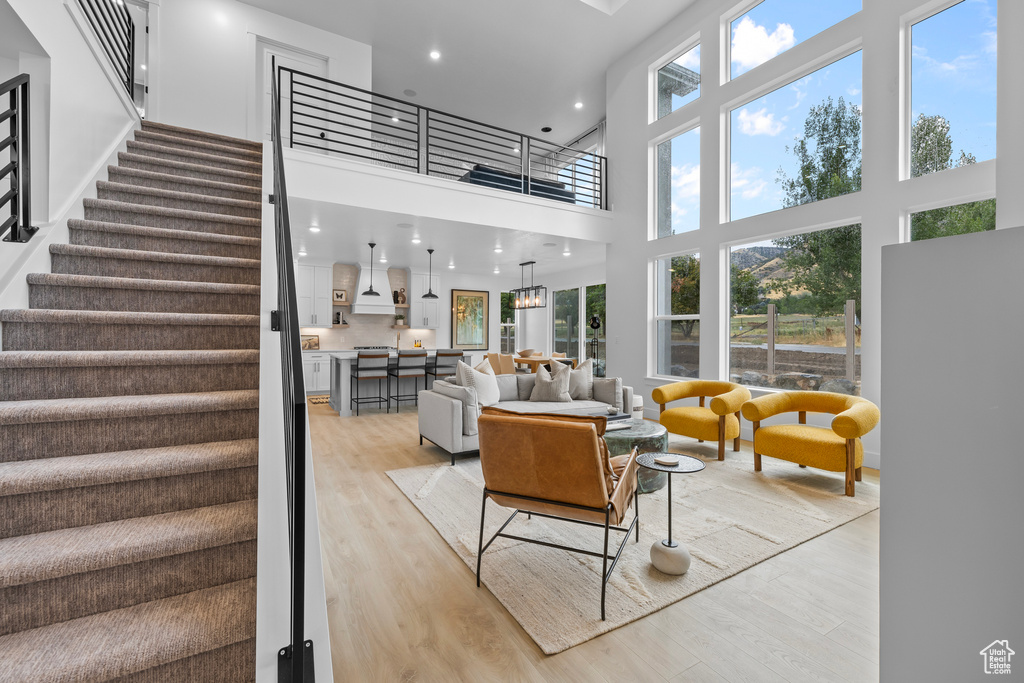 Living area with light wood-style floors, stairs, a high ceiling, and recessed lighting