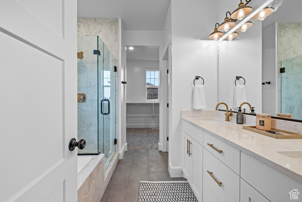 Bathroom featuring a marble finish shower, tile patterned floors, and double vanity