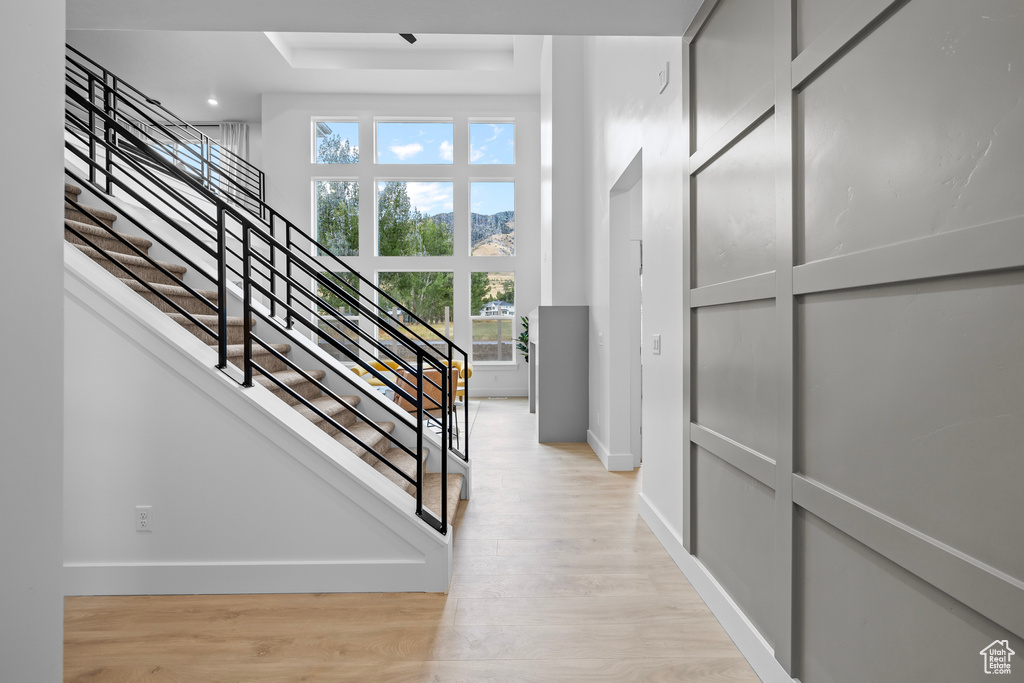 Staircase with baseboards, wood finished floors, and a raised ceiling