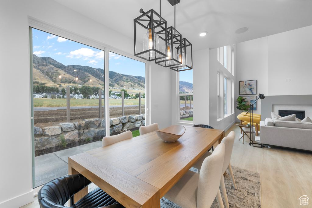 Dining area with a mountain view, light wood-style floors, a glass covered fireplace, a chandelier, and recessed lighting