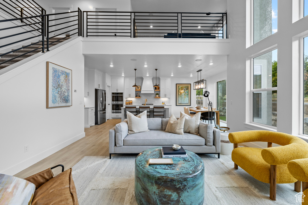 Living area featuring a high ceiling, baseboards, light wood-type flooring, recessed lighting, and a chandelier