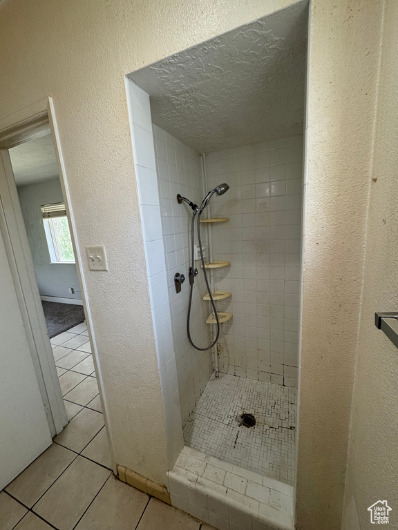 Full bath featuring a shower stall, tile patterned floors, a textured ceiling, and a textured wall