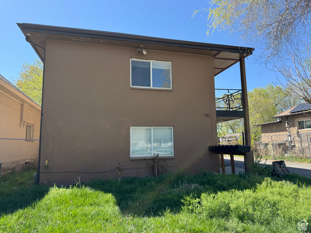 View of home's exterior with fence, a balcony, and concrete block siding