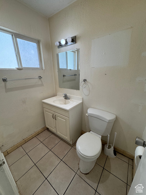 Half bathroom featuring toilet, vanity, and tile patterned floors