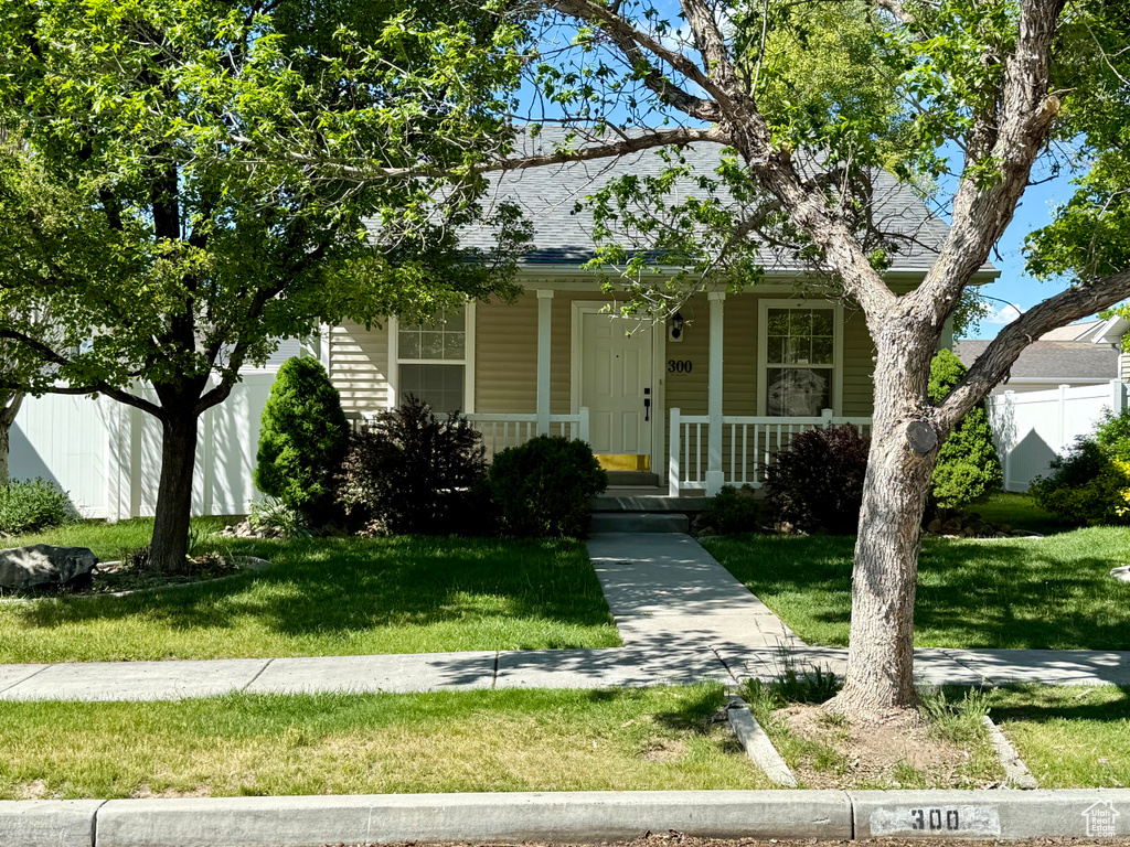 View of front of property featuring a front lawn, a shingled roof, and a porch