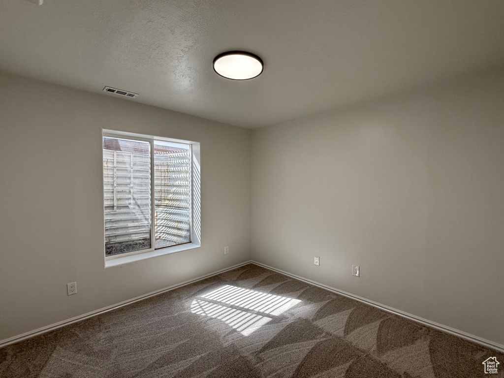 Unfurnished room with dark carpet and baseboards