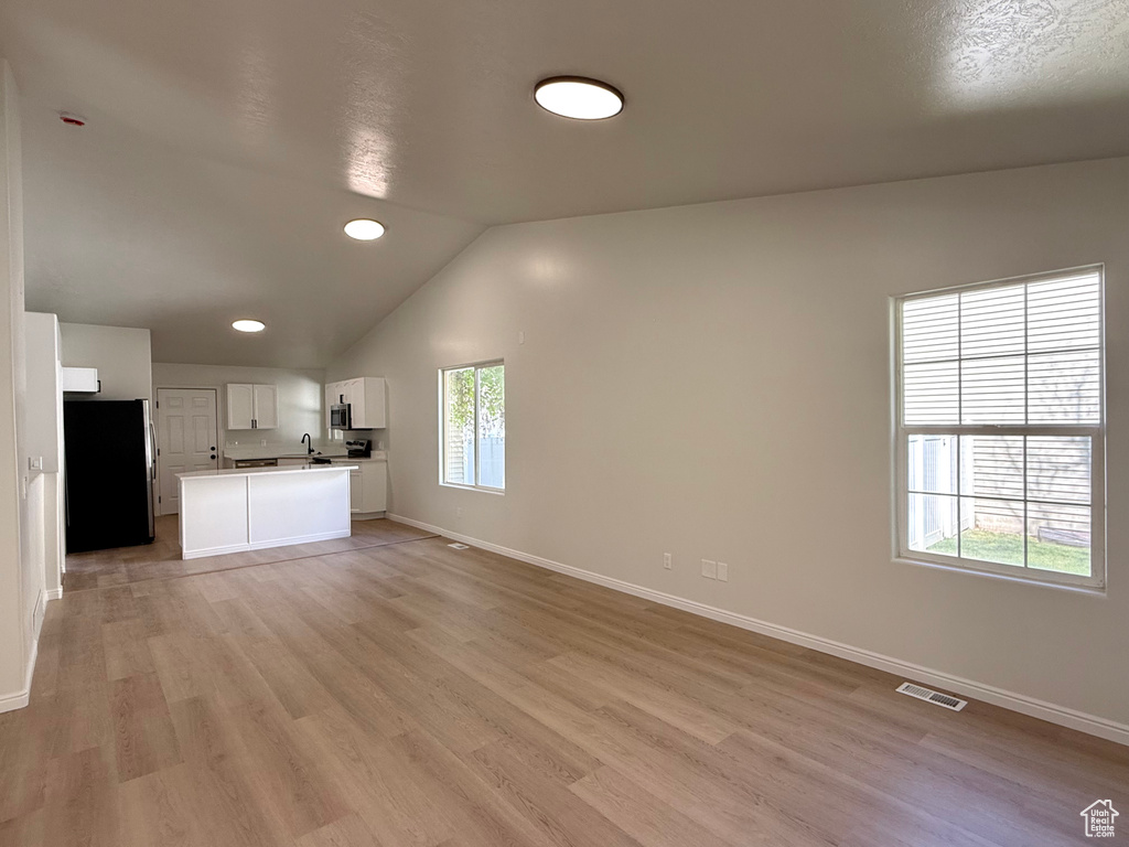 Unfurnished living room featuring light wood-style floors, vaulted ceiling, baseboards, and recessed lighting