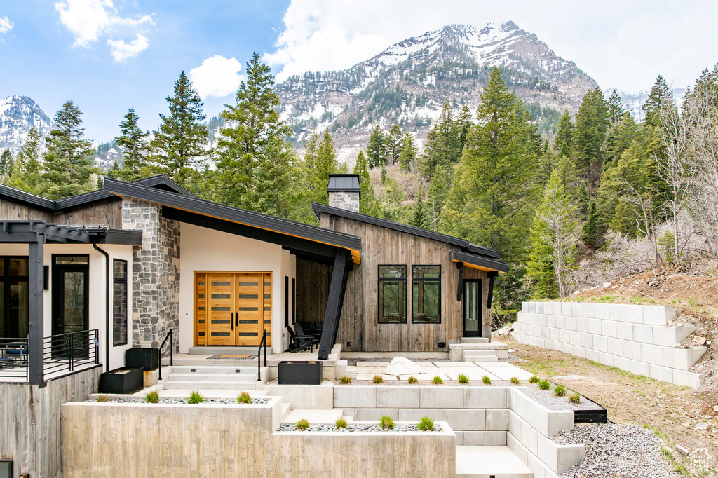 View of front facade with a chimney, a mountain view, and stone siding