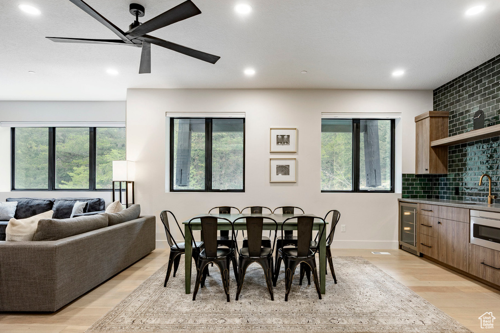 Dining room with ceiling fan, light wood-style floors, recessed lighting, baseboards, and wine cooler