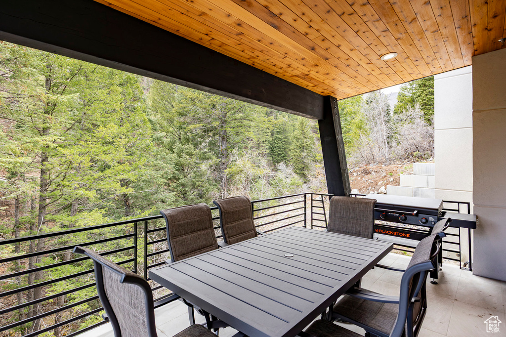 View of patio with a balcony, a forest view, and outdoor dining area
