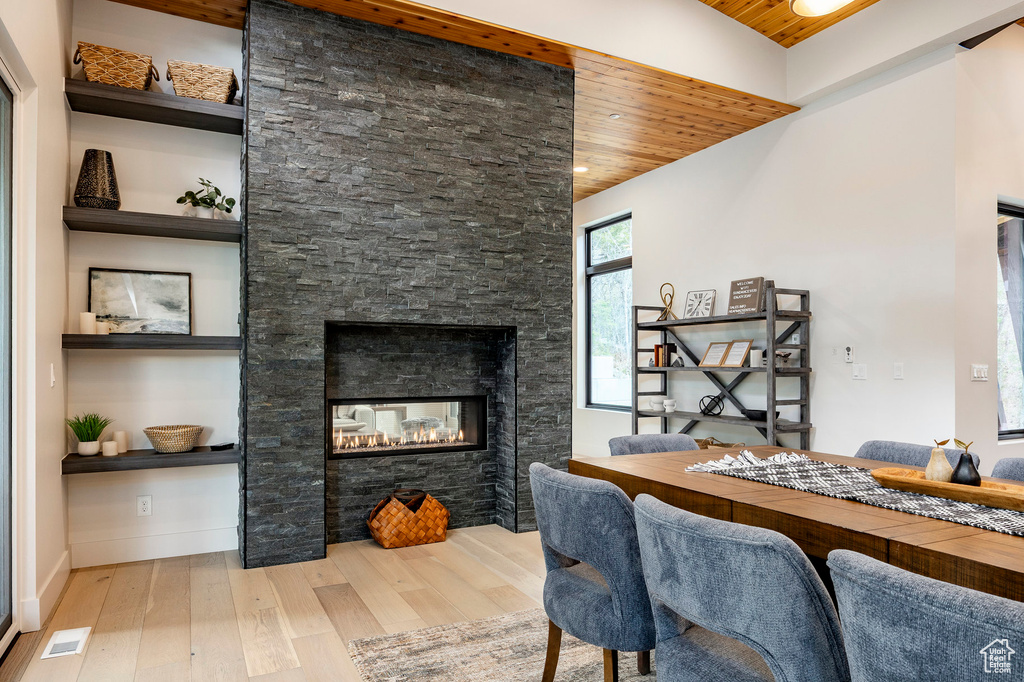 Dining area featuring wooden ceiling, hardwood / wood-style flooring, a stone fireplace, baseboards, and recessed lighting
