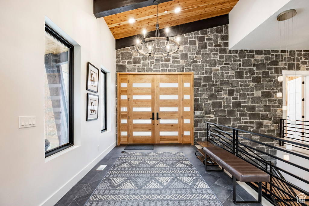 Entrance foyer featuring a chandelier, wood ceiling, french doors, a high ceiling, and baseboards
