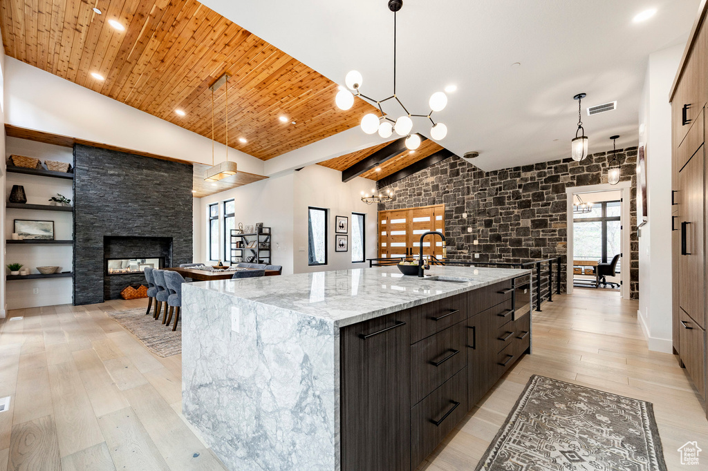 Kitchen with a sink, modern cabinets, a large island, light wood-style floors, and wood ceiling