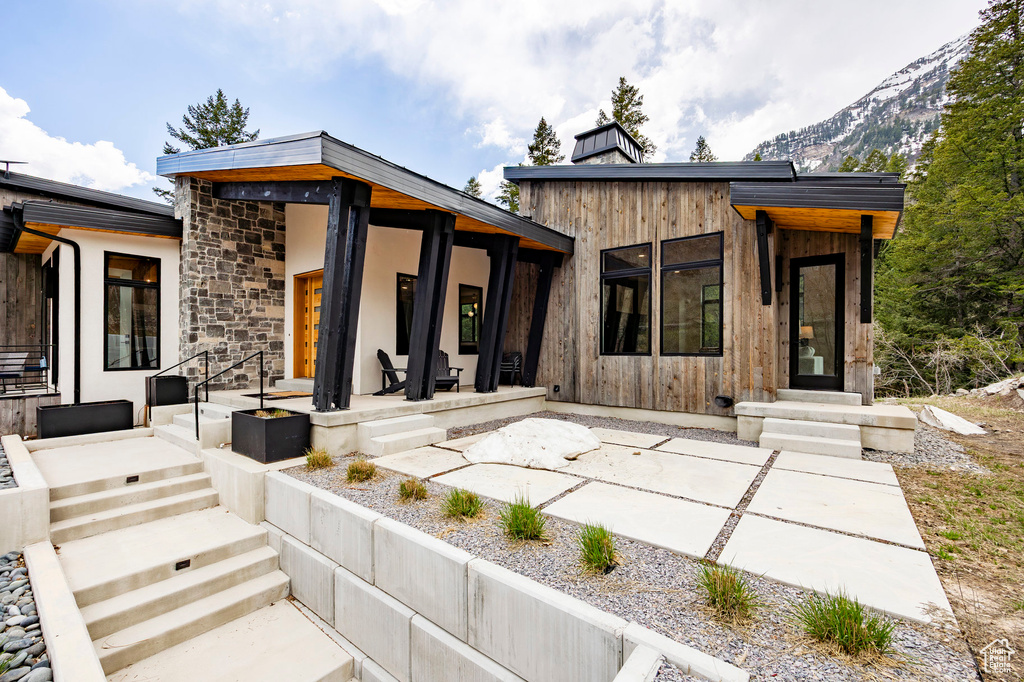 Back of property featuring a patio, stone siding, and a mountain view