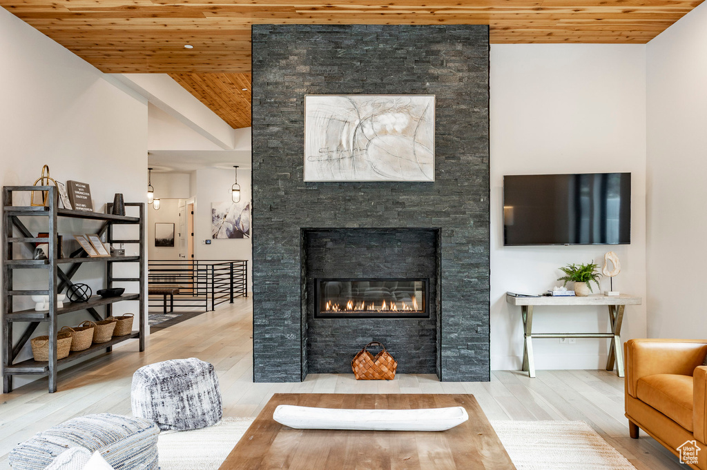 Living area with wooden ceiling, a stone fireplace, and wood finished floors