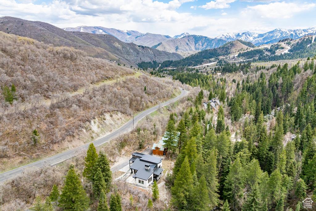Aerial view of property and surrounding area featuring a mountainous background and a forest