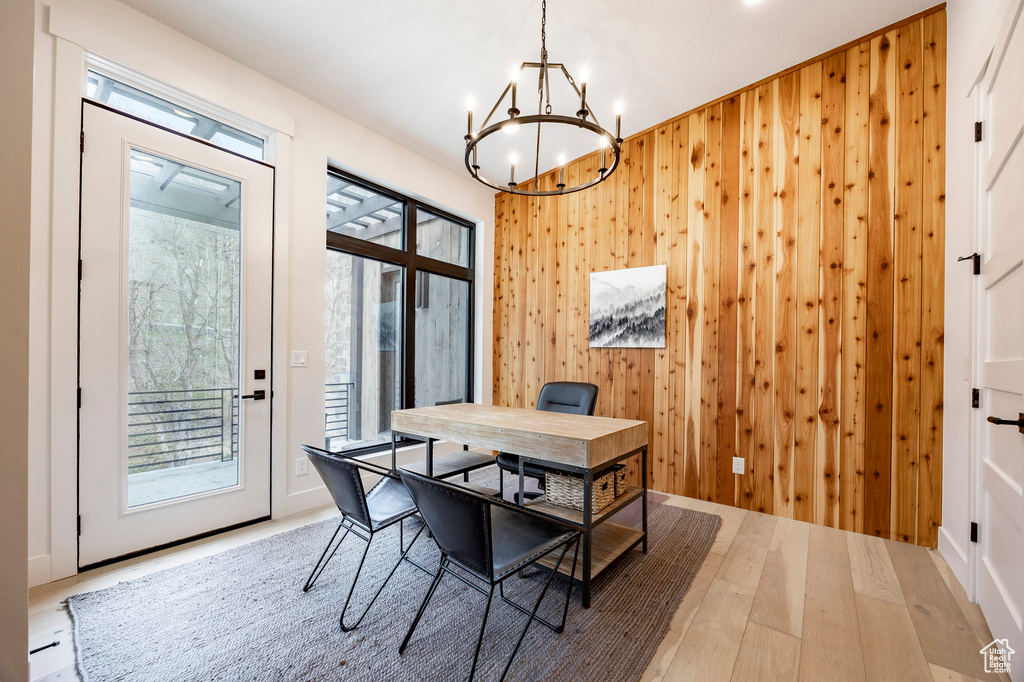 Dining room with a chandelier, wood walls, wood finished floors, and an office area