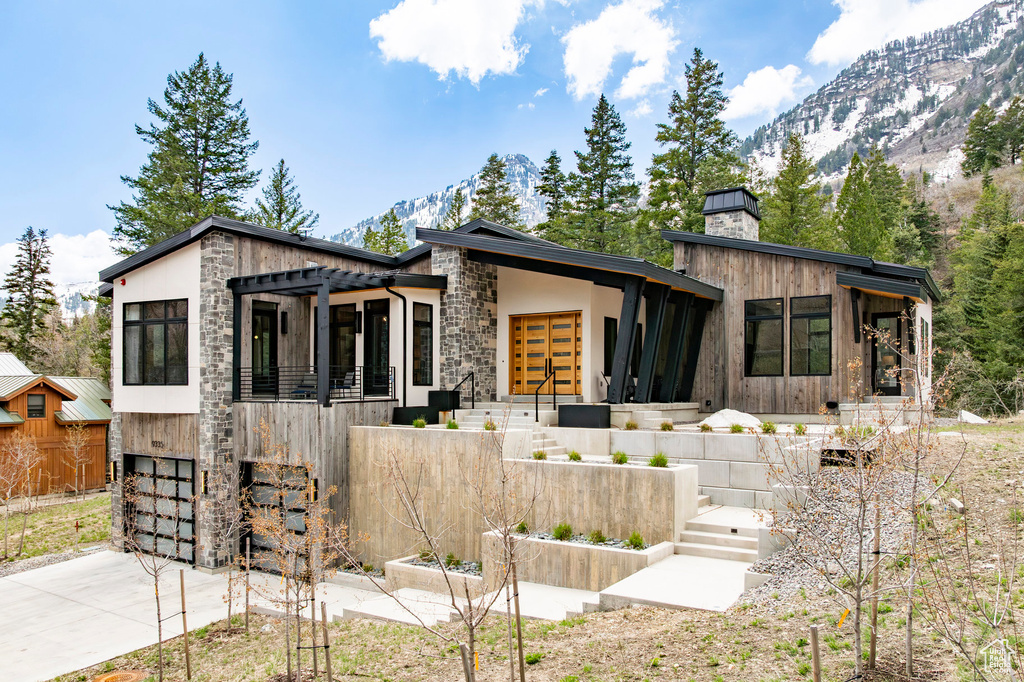 Modern home with a garage, stone siding, driveway, and a mountain view