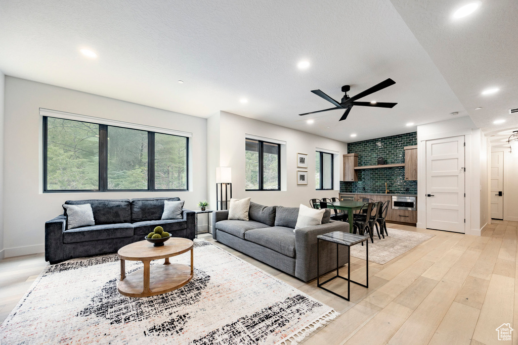 Living area with ceiling fan, recessed lighting, light wood-style flooring, and baseboards