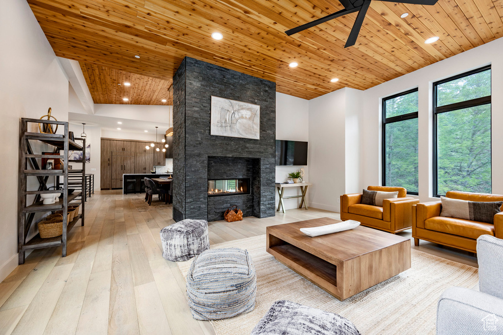 Living area with light wood-type flooring, wooden ceiling, ceiling fan, recessed lighting, and a stone fireplace