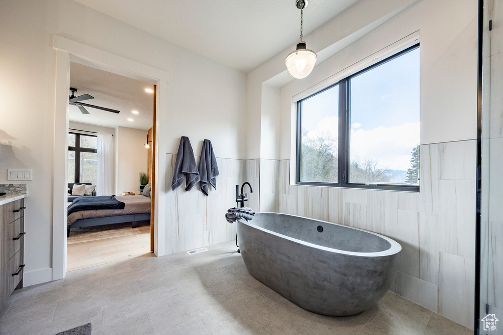 Ensuite bathroom with a freestanding bath, wainscoting, ceiling fan, tile walls, and recessed lighting