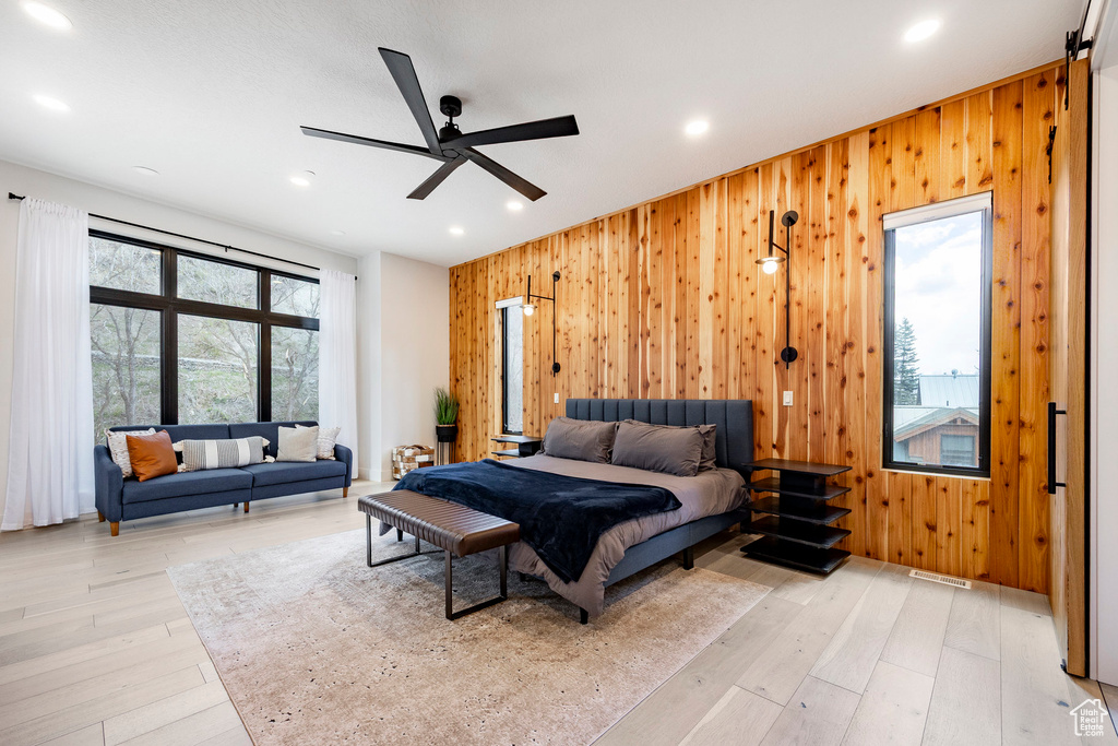 Bedroom with wood walls, light wood-style floors, recessed lighting, and ceiling fan