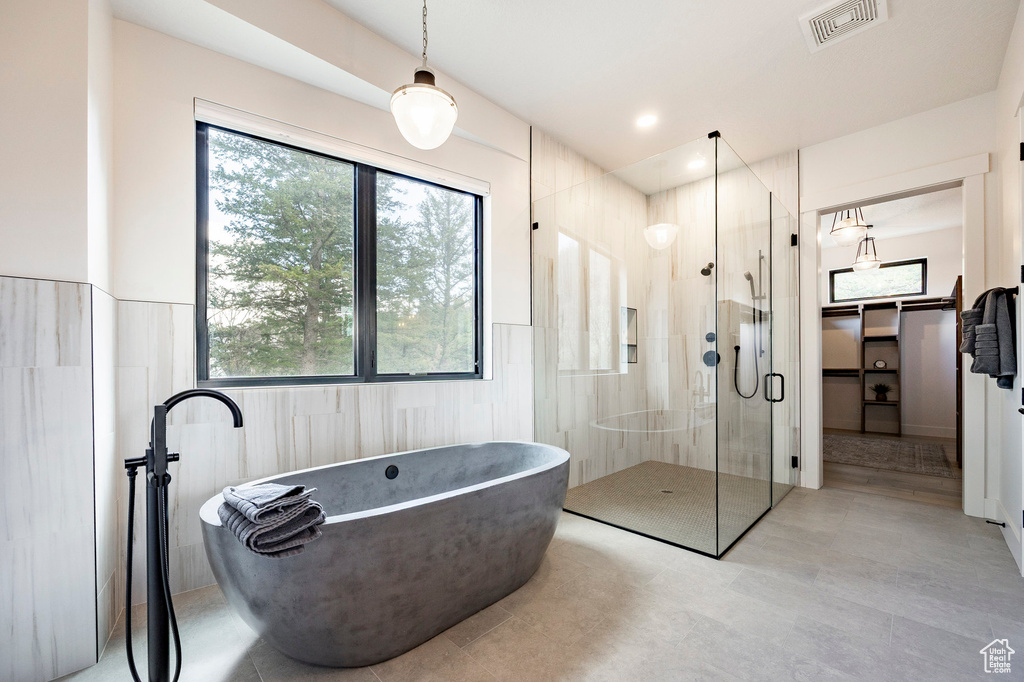 Bathroom featuring a stall shower, a freestanding tub, and tile patterned flooring