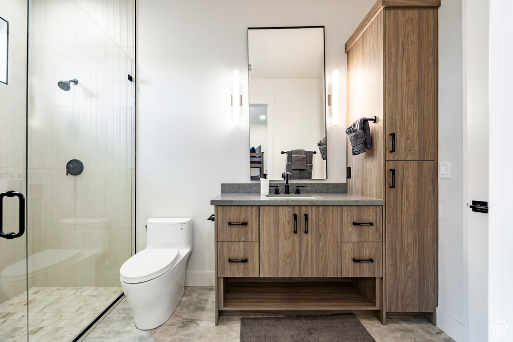 Bathroom with a shower stall, toilet, vanity, and baseboards