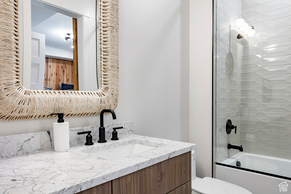 Bathroom featuring toilet, vanity, and  shower combination