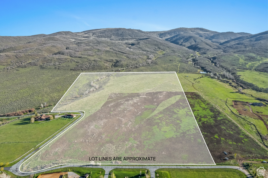 Aerial view of property and surrounding area with property parcel outlined and a mountain backdrop