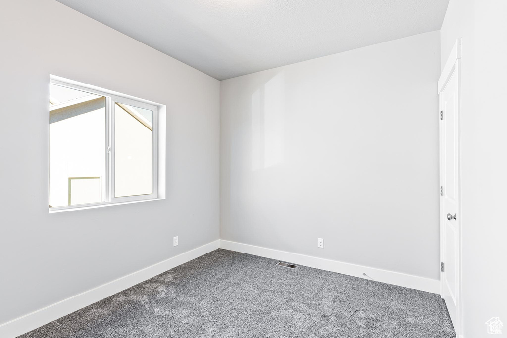 Empty room with dark carpet and baseboards