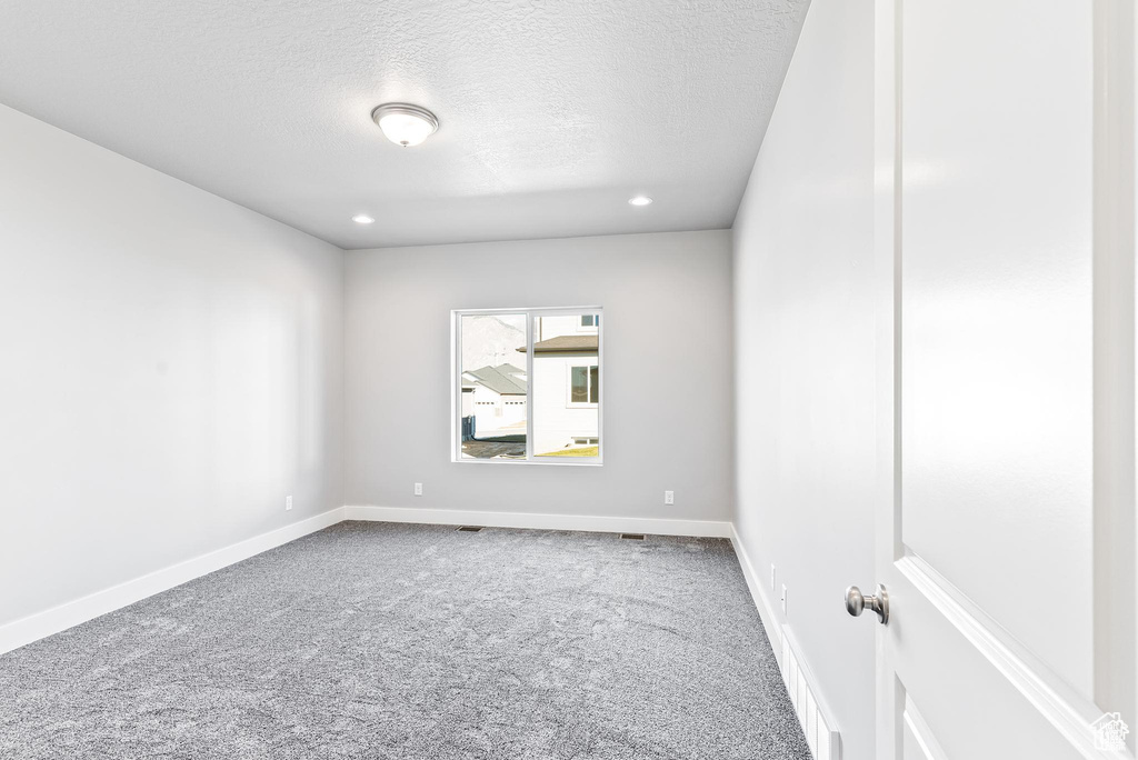 Empty room with carpet flooring, a textured ceiling, baseboards, and recessed lighting