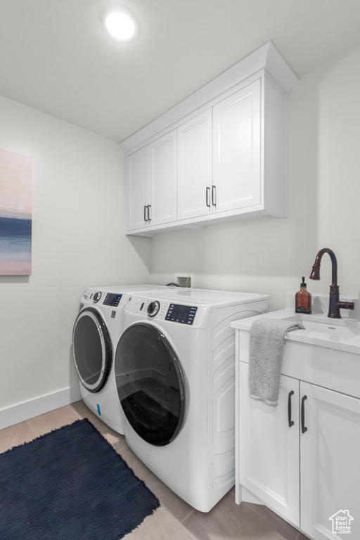 Laundry room featuring washing machine and dryer, cabinet space, and baseboards