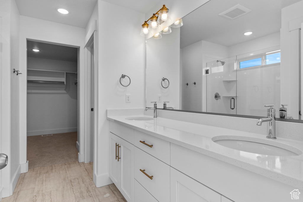 Bathroom with a stall shower, a spacious closet, double vanity, recessed lighting, and baseboards