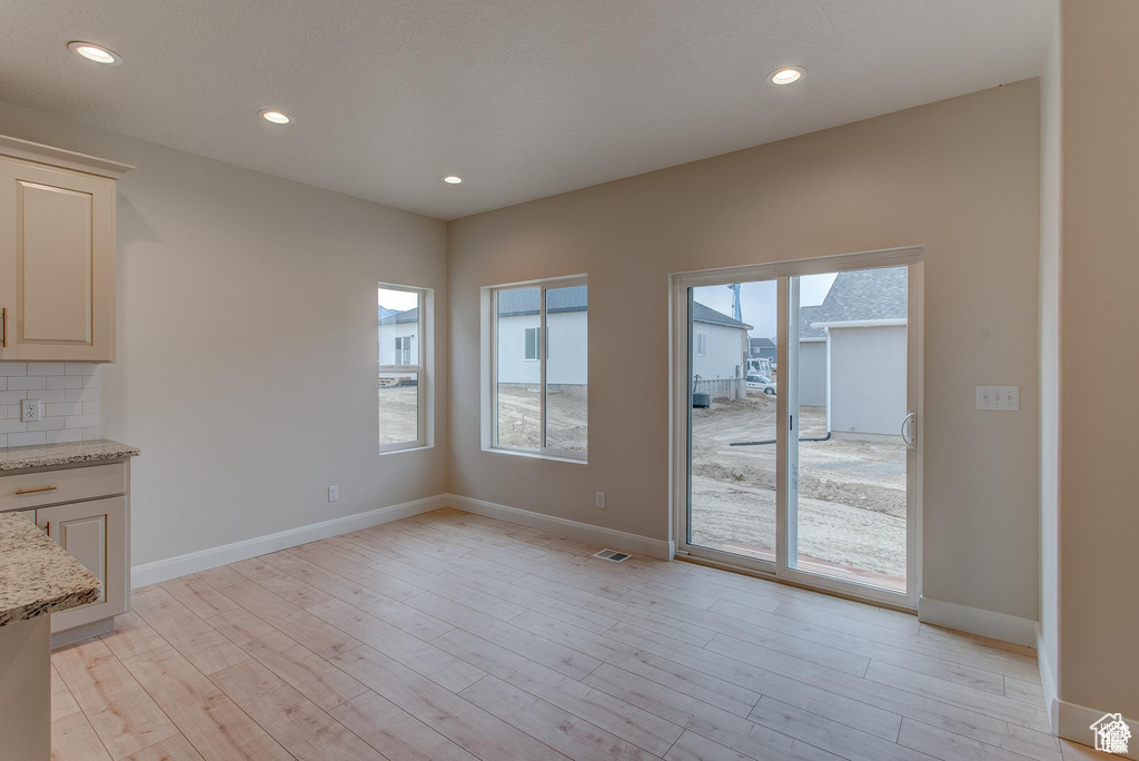 Unfurnished dining area with light wood-style floors, recessed lighting, and baseboards