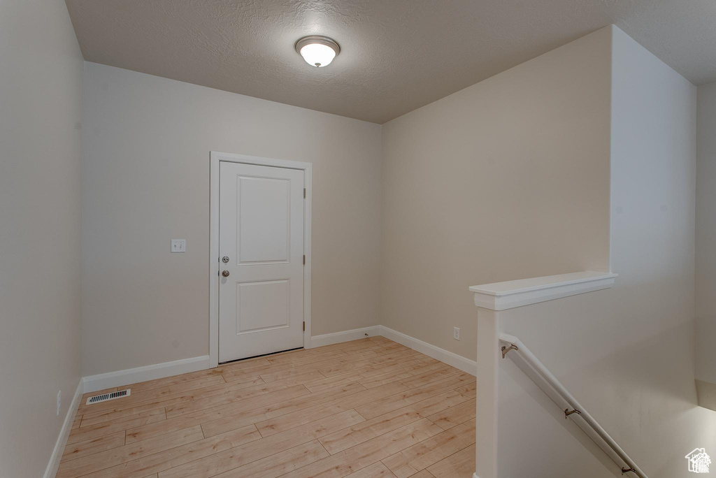 Empty room featuring light wood-style flooring, baseboards, and a textured ceiling