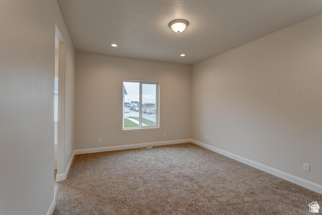 Carpeted spare room featuring baseboards, recessed lighting, and a textured ceiling
