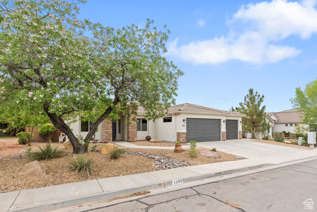 View of front of home featuring driveway, a garage, stucco siding, and stone siding