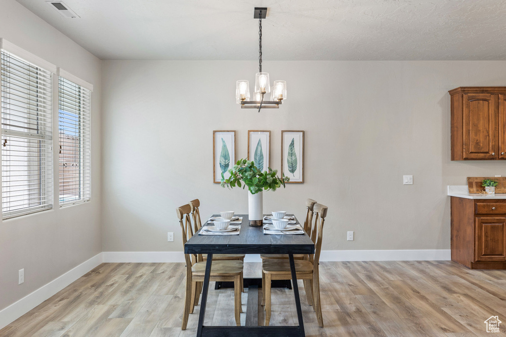 Dining space with light wood finished floors, plenty of natural light, a chandelier, and baseboards