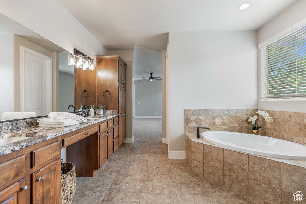 Bathroom with double vanity, a bath, ceiling fan, and baseboards