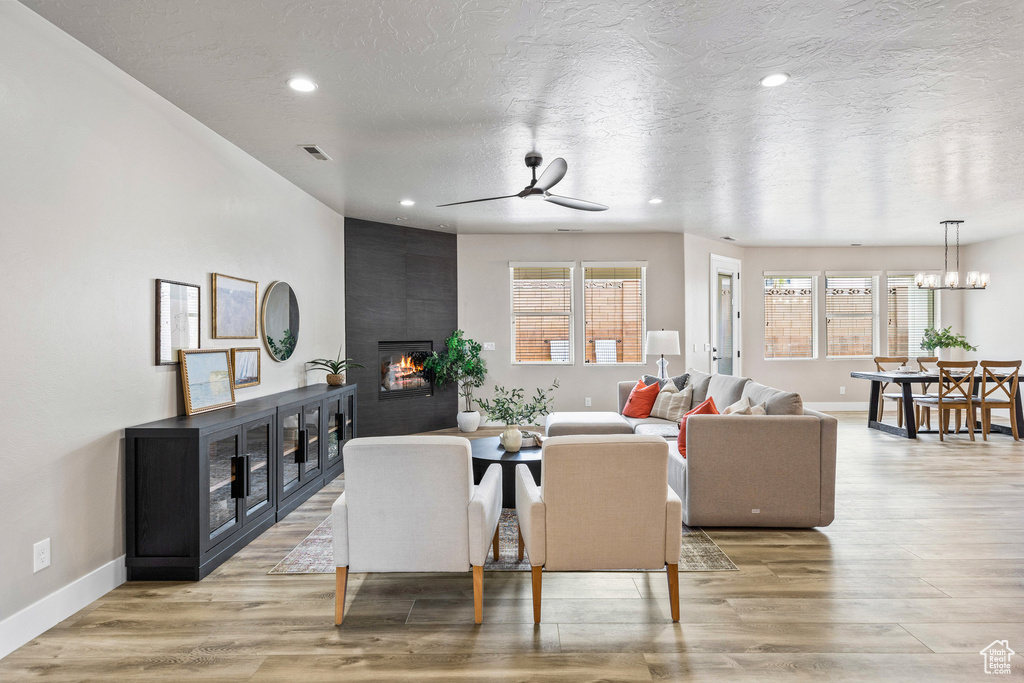 Living room featuring healthy amount of natural light, a fireplace, a ceiling fan, baseboards, and a textured ceiling
