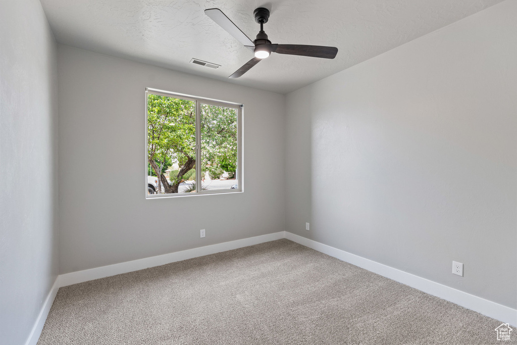 Carpeted empty room with a ceiling fan and baseboards