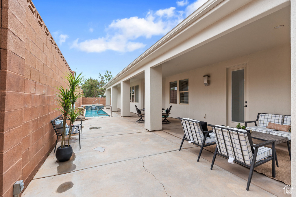 View of patio featuring outdoor dining space, a fenced backyard, and a pool with connected hot tub