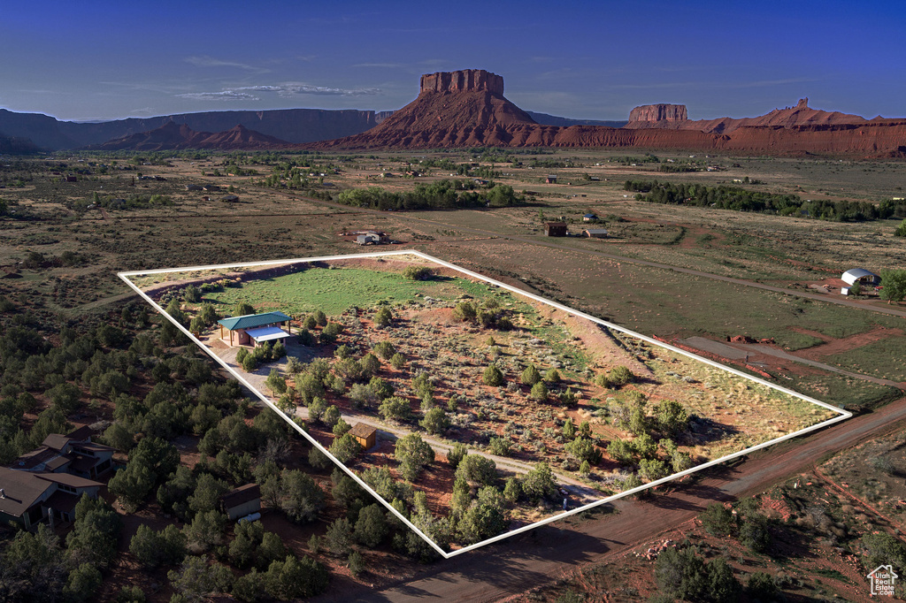 Aerial view of property and surrounding area featuring property parcel outlined, rural landscape, and mountains